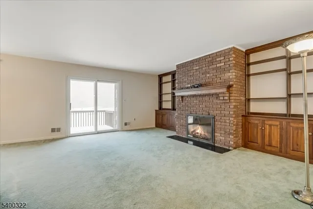 a view of an empty room with a fireplace and window