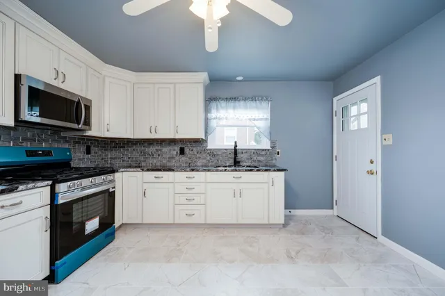 a kitchen with granite countertop white cabinets white stainless steel appliances and a sink