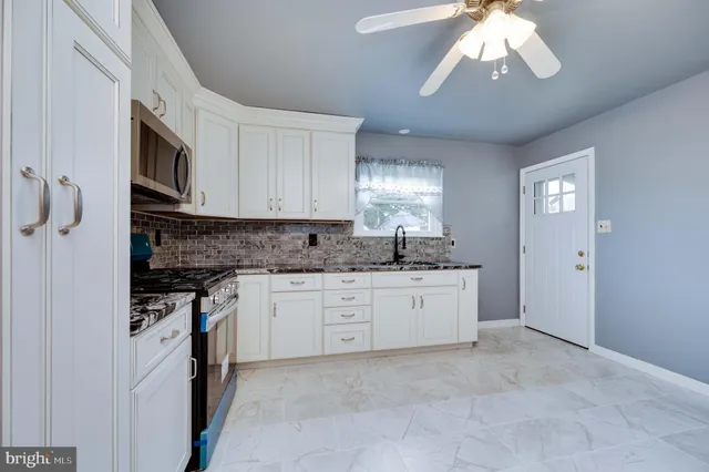 a kitchen with granite countertop a stove a sink and a refrigerator