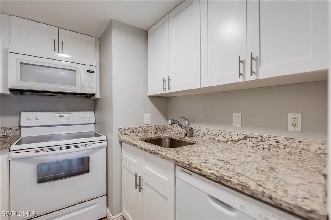2117 Gulf Beach Villas Captiva, FL 33924 - Photo 12 of 24 a kitchen with granite countertop white cabinets and a stove