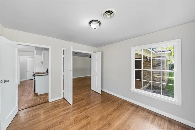 an empty room with wooden floor and windows