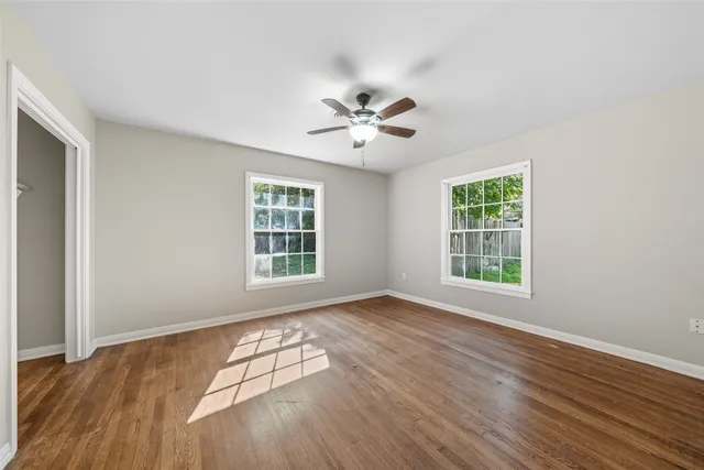 an empty room with wooden floor and windows