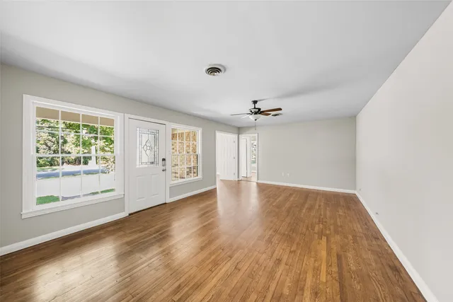 a view of an empty room with a window and wooden floor