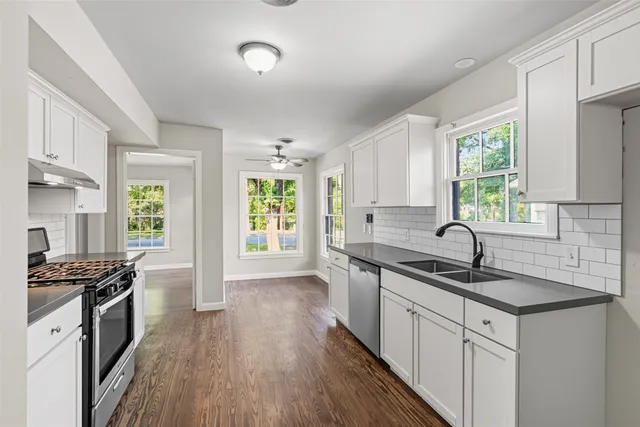 a kitchen with granite countertop a sink stainless steel appliances a window and a counter top space
