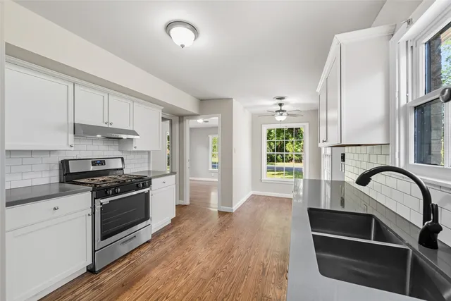 a kitchen with kitchen island granite countertop a stove and a wooden floors