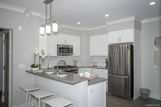 a kitchen with stainless steel appliances a sink a refrigerator a stove a microwave a dining table and chairs