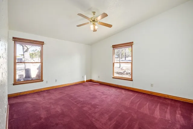 an empty room with windows and ceiling fan