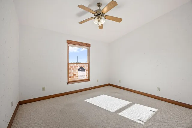 an empty room with a window and a ceiling fan