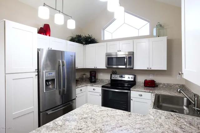 a kitchen with stainless steel appliances granite countertop a refrigerator sink and stove