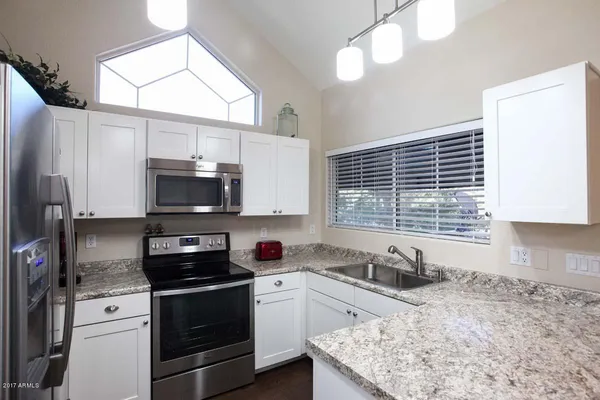 a kitchen with stainless steel appliances granite countertop a sink a stove a refrigerator cabinets and a window