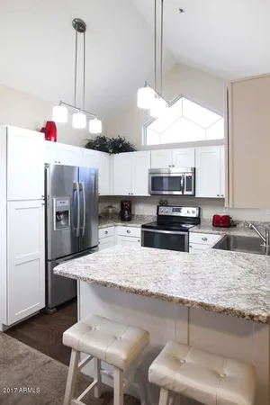 a kitchen with stainless steel appliances kitchen island granite countertop a sink and white cabinets