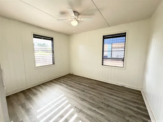 an empty room with wooden floor and fan