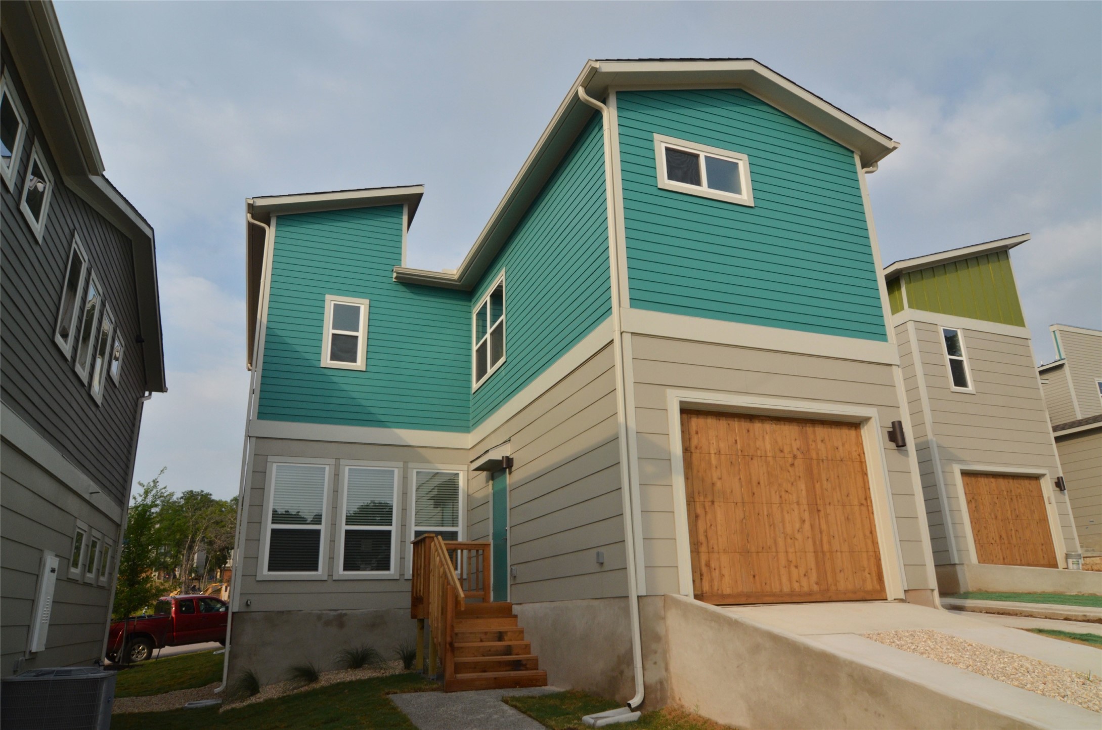 1916 Cleese Drive Austin, TX 78741 - Photo 29 of 36 Modern architecture with a wooden garage door and vibrant teal siding creates a striking facade.