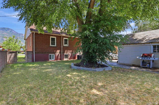 85 North 800 West Provo, UT 84601 - Photo 2 of 25 Expansive backyard featuring a mature shade tree, a concrete patio, and a detached structure with siding