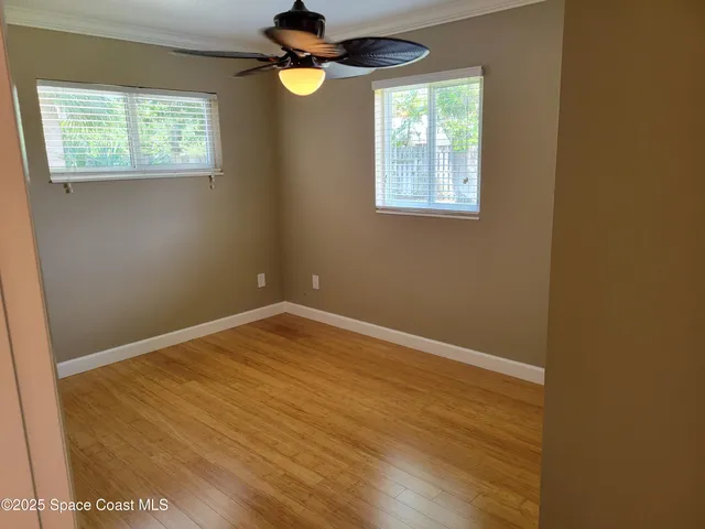an empty room with wooden floor and windows
