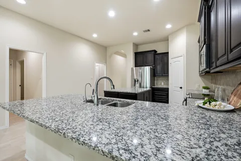 a kitchen with stainless steel appliances granite countertop a sink a stove and a refrigerator