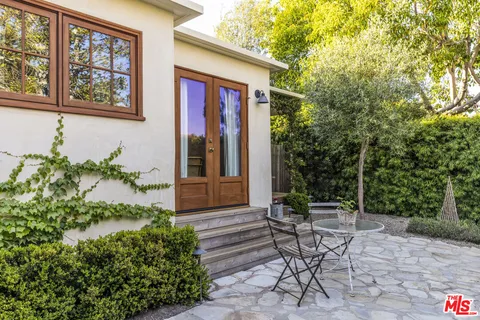 a patio with table and chairs and potted plants