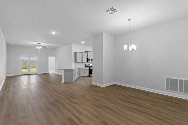 a view of an empty room with wooden floor and a ceiling fan