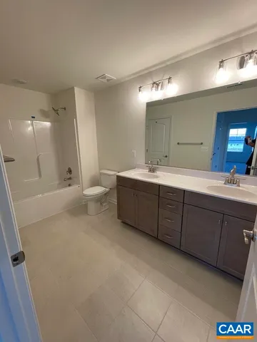 a bathroom with a double vanity sink a toilet and a mirror