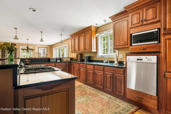 a kitchen with stainless steel appliances kitchen island granite countertop a stove top oven a sink a dining table and chairs with wooden floor
