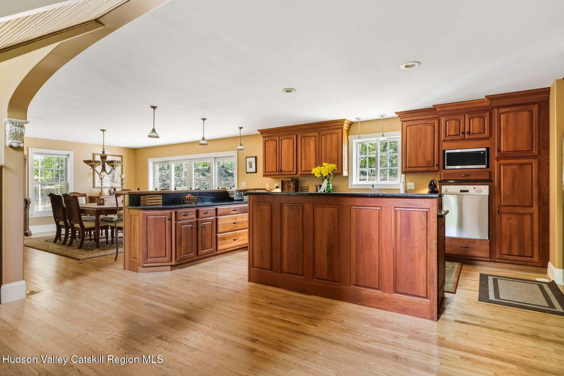 74 Bellevue Road Highland, NY 12528 - Photo 50 of 65 a kitchen with stainless steel appliances kitchen island granite countertop a stove top oven a sink a dining table and chairs with wooden floor