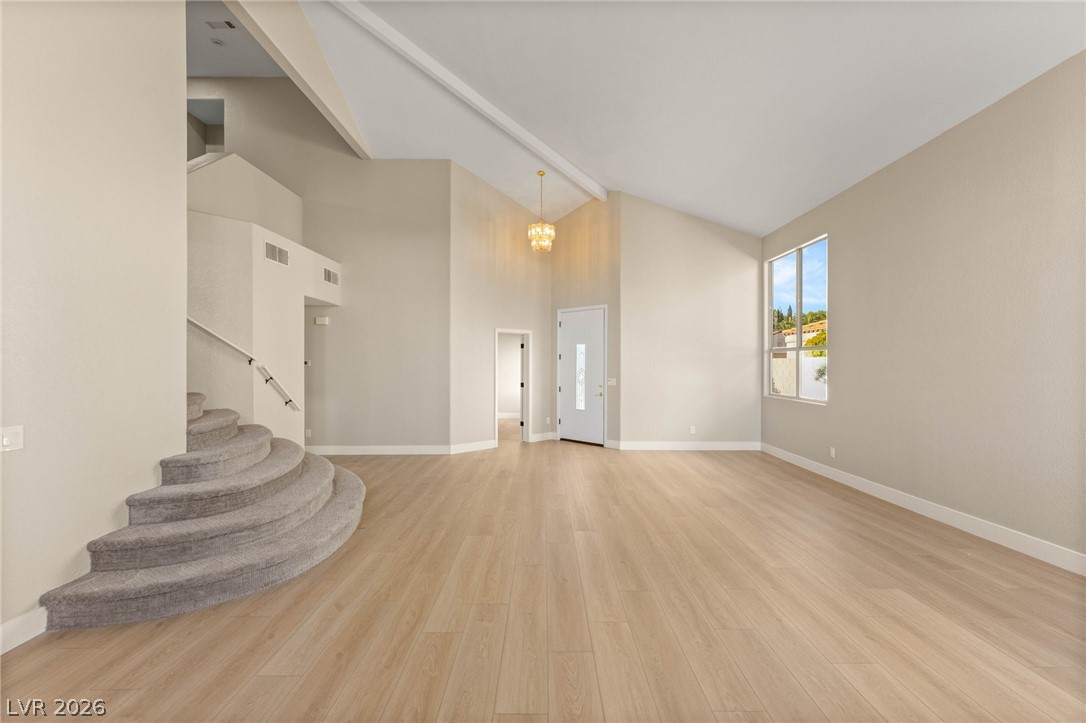 2104 Inverness Drive Henderson, NV 89074 - Photo 8 of 51 Unfurnished living room with light wood finished floors, stairway, and high vaulted ceiling