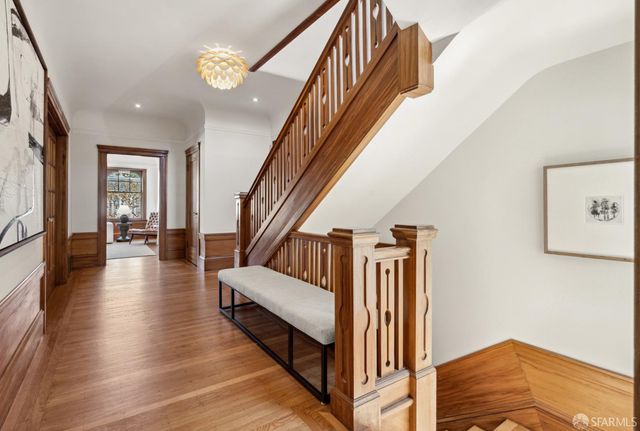 a view of staircase with lots of frames on wall and wooden floor