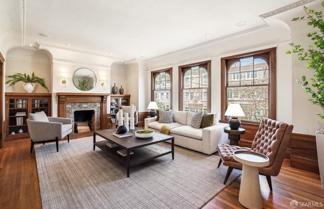 a living room with furniture a rug a fireplace and a large window