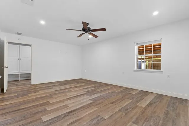 a view of empty room with wooden floor and fan