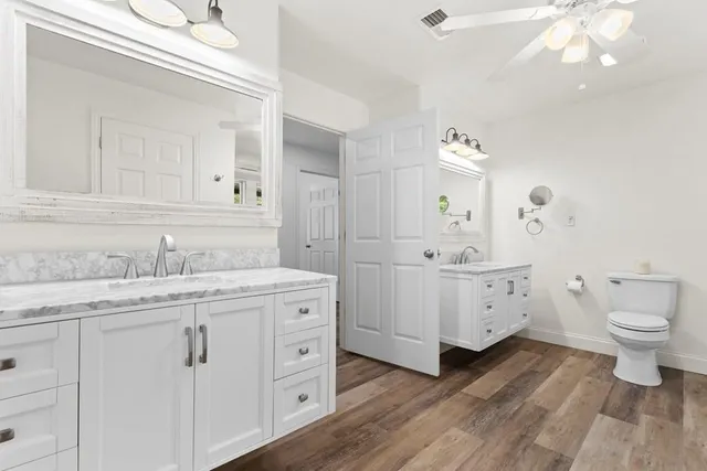 a bathroom with double vanity sink a mirror and a toilet
