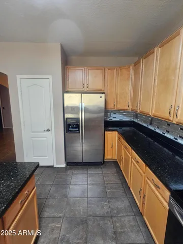 a kitchen with granite countertop a refrigerator and a sink