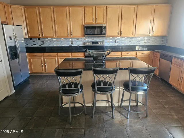 a kitchen with stainless steel appliances granite countertop a stove a sink and a refrigerator