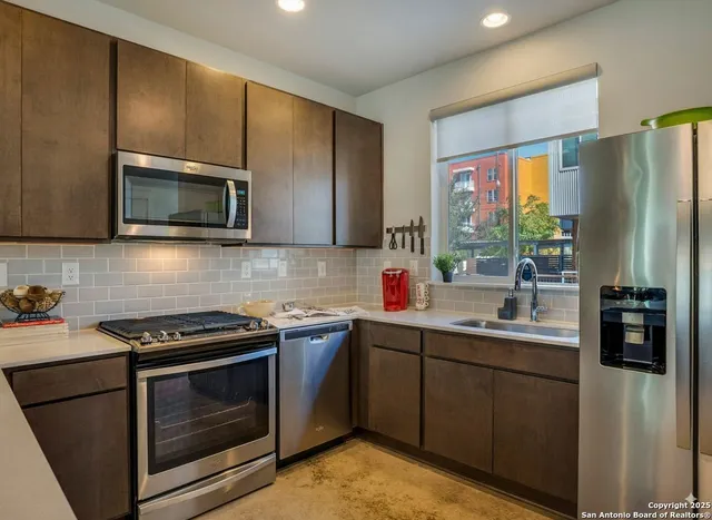 a kitchen with stainless steel appliances a stove microwave sink and refrigerator