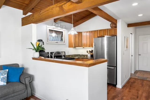 a kitchen with stainless steel appliances granite countertop a refrigerator a sink a stove and a dining table