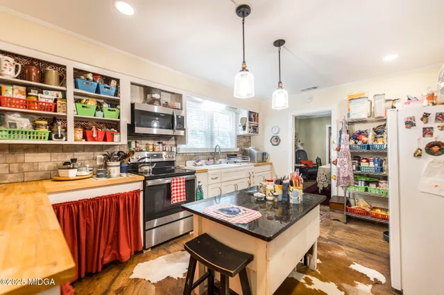 a kitchen with stainless steel appliances granite countertop a stove refrigerator and a dining table with wooden floor