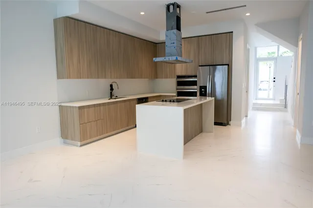 a kitchen with stainless steel appliances a sink a stove a refrigerator cabinets and a dining table