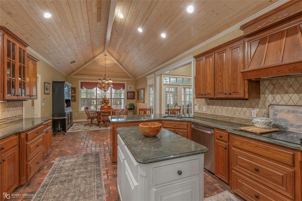 400 Crouch Road Benton, LA 71006 - Photo 19 of 40 Kitchen featuring appliances with stainless steel finishes, crown molding, dark stone counters, brick floors, and brown cabinetry