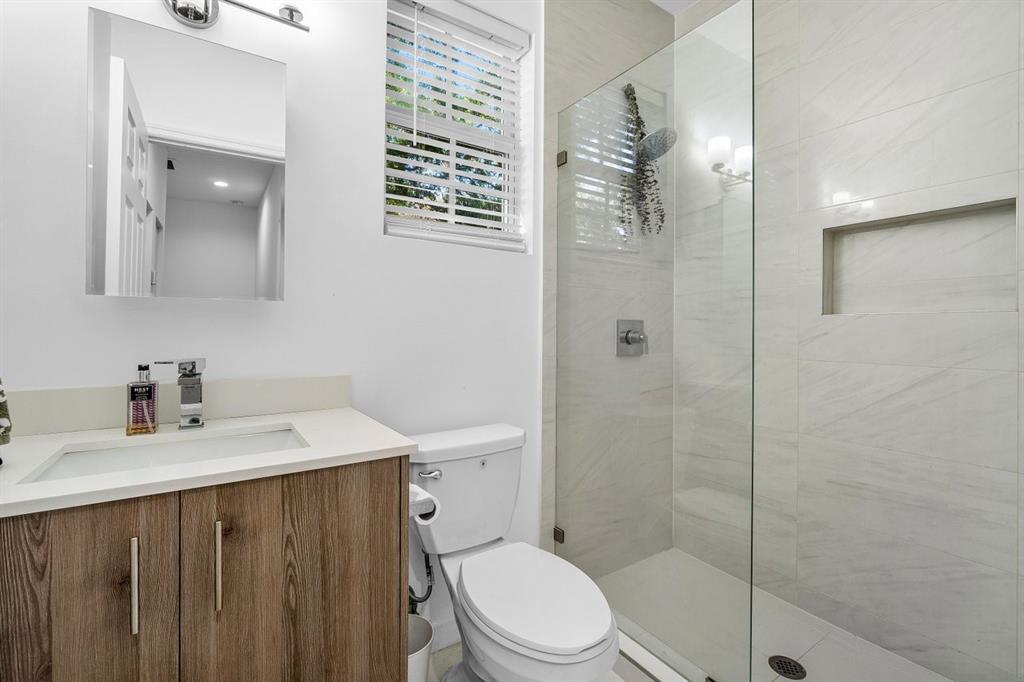 1030 Crystal Way, Unit 104 Delray Beach, FL 33444 - Photo 21 of 44 a bathroom with a sink a toilet and shower