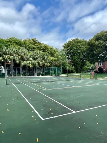 a view of a tennis ground with large trees