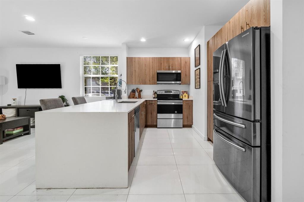 1030 Crystal Way, Unit 104 Delray Beach, FL 33444 - Photo 5 of 44 a kitchen with stainless steel appliances a refrigerator stove microwave and sink