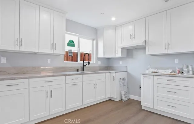 a kitchen with white cabinets and sink