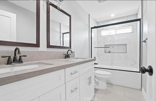 a bathroom with a granite countertop sink mirror vanity and toilet