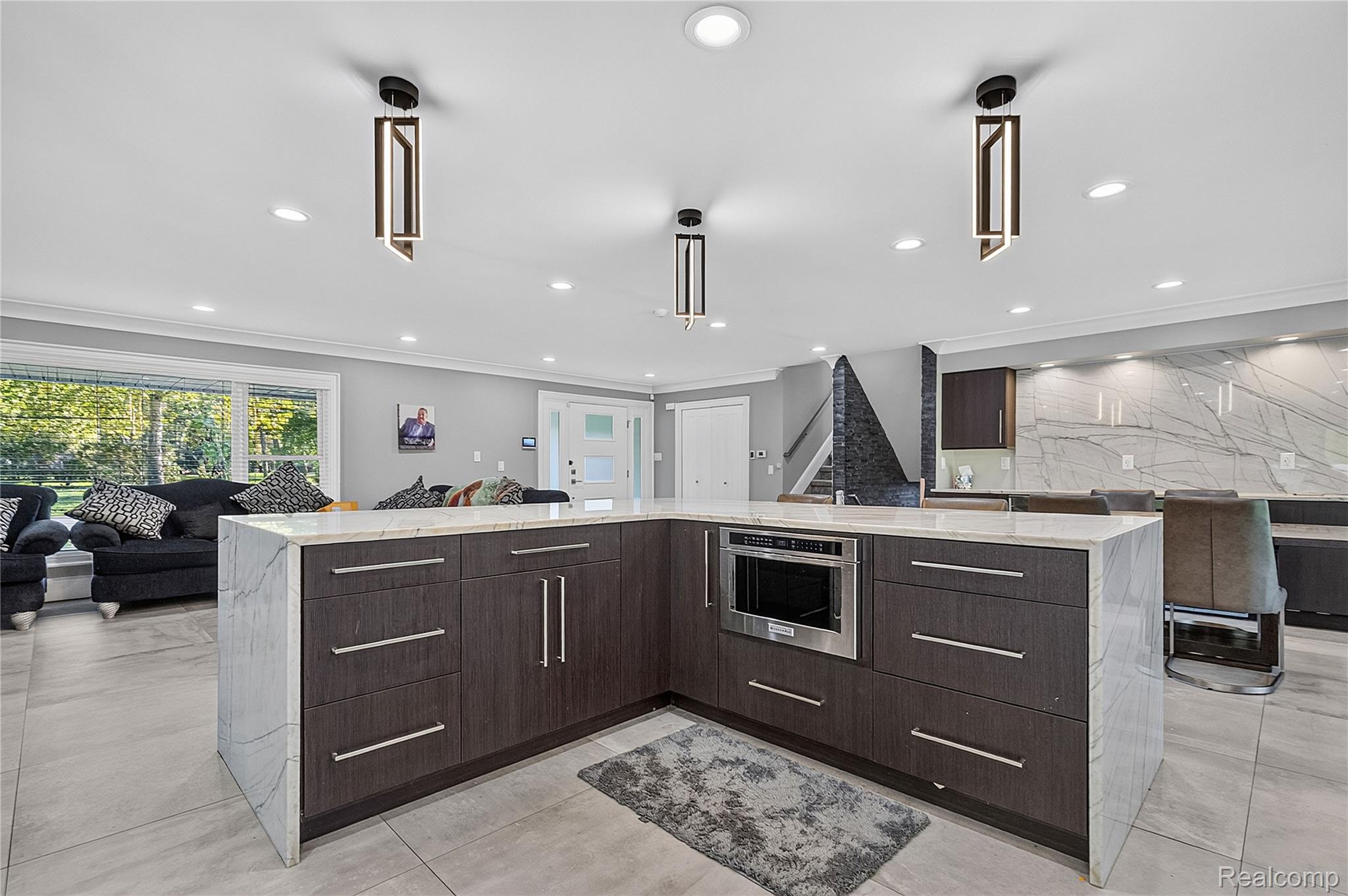 15879 Millar Road Clinton Township, MI 48036 - Photo 10 of 65 Expansive kitchen island featuring a waterfall countertop, integrated microwave, and dark wood-finish cabinetry