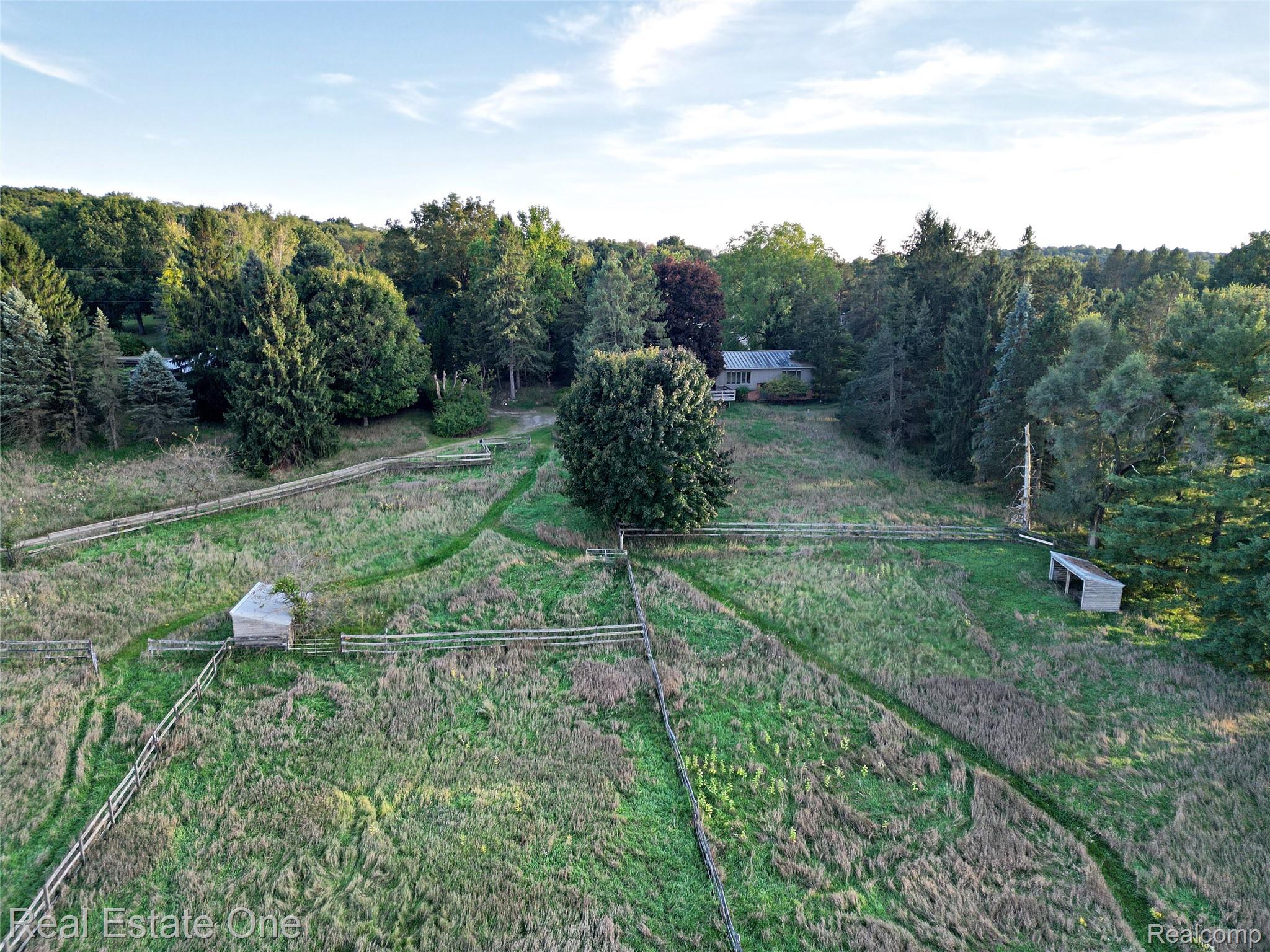 895 Rowe Road Milford, MI 48380 - Photo 47 of 50 Expansive grass-covered terrain with established fencing, two outbuildings, and a backdrop of mature trees