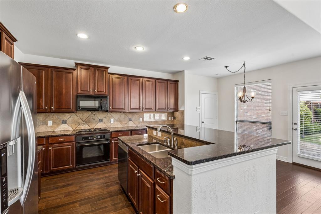 960 Remuda Road Frisco, TX 75033 - Photo 26 of 39 Kitchen featuring dark wood cabinetry, stainless steel refrigerator, black range, and granite countertops