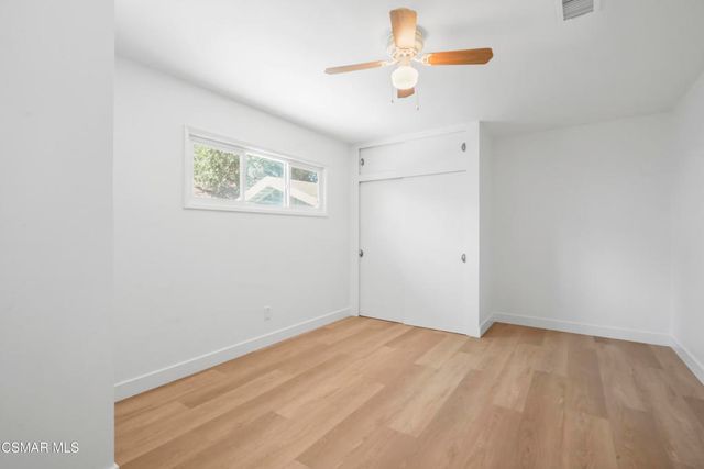 an empty room with a window and a fan