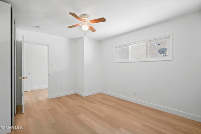 an empty room with a ceiling fan and wooden floor