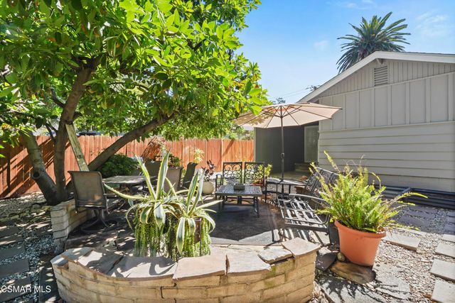 a backyard of a house with table and chairs potted plants