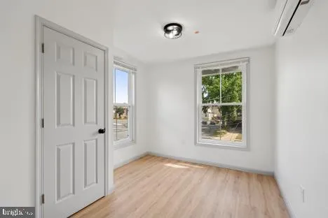 an empty room with wooden floor cabinet and windows