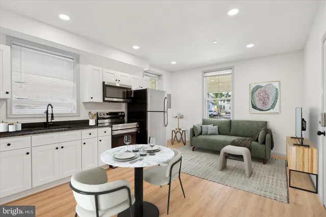 a living room with furniture a refrigerator and a dining table with wooden floor